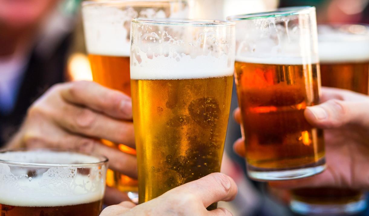 Close up of hands holding three pints of beer