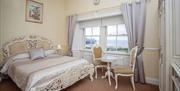 Interior of a luxury double bedroom with double bed, table and chairs and a sea view