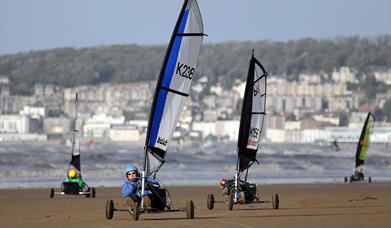 Four Blo-karts or land yachts racing along a sandy beach