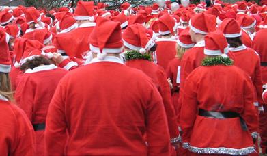 Dozens of people dressed in red Santa suits ready to start a fun run