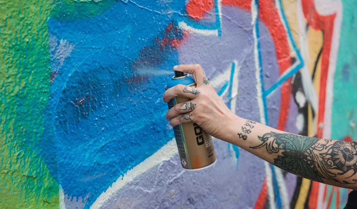 A street artist paint spraying a wall