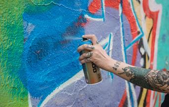 A street artist paint spraying a wall