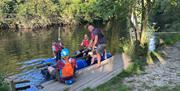 People on a riverbank boarding a raft