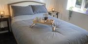 A double bedroom with a full breakfast tray on the grey bed