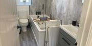 Modern grey bathroom with basin, bath, towel rail and toilet
