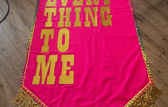 A photograph of a bright pink banner with lyrics on it.