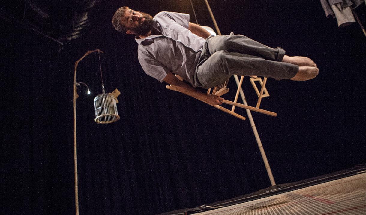 Man floats in air on a chair, dark surrounding