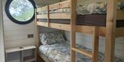 Wooden bunk bed in a a wooden glamping pod with a round window