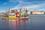 The Mersey Ferries brightly coloured Dazzle Ferry sailing on the Mersey River on a blue sky day. The iconic Liverpool skyline is behind the ferry.