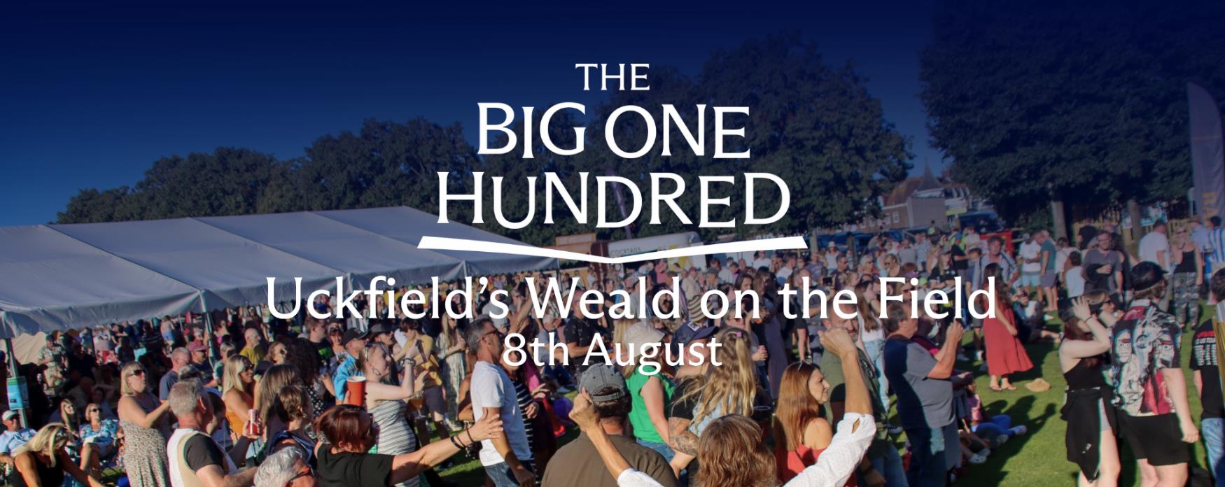 Crowd gathered at an outdoor event with tents and stalls, with “The Big One Hundred – Uckfield’s Weald on the Field 8th August” text overlaid.