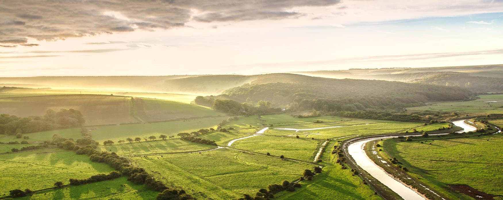 green hills bathed in sunlight with a winding river