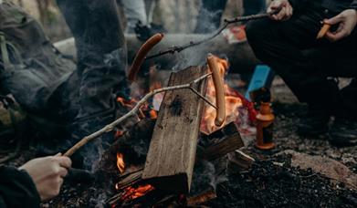 Group of people having a bbq around camp fire