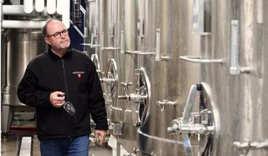 Image of a man walking through the tanks that make wine