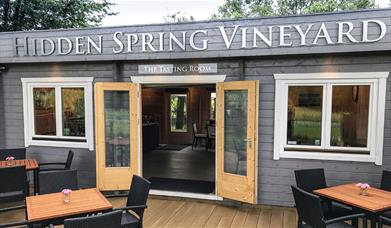 image of the vineyard tasting room - a wooden building with seating outside and inside