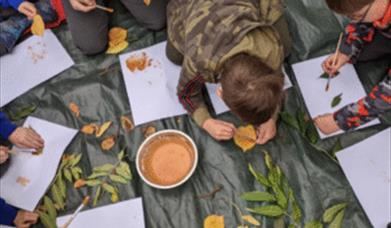 kids making creative pieces with leaves and paint