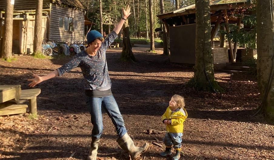 A mum dancing while a toddler looks on