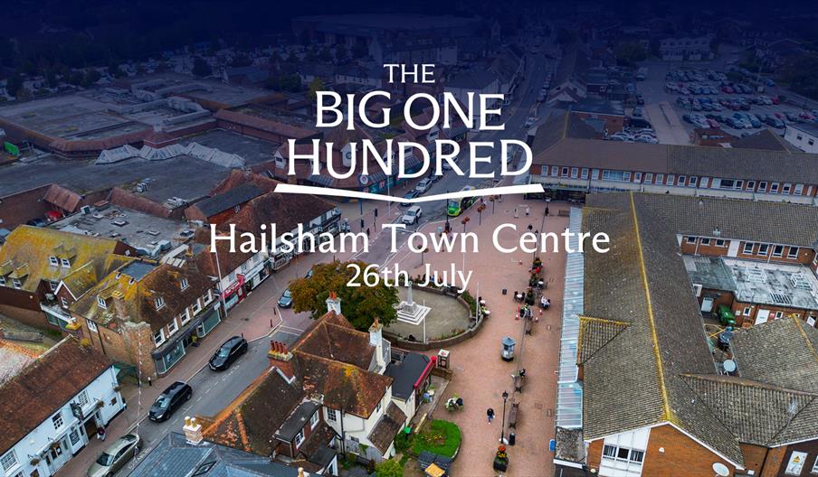 Aerial view of Hailsham Town Centre showing streets, shops and a central square, with “The Big One Hundred – Hailsham Town Centre 26th July” text over