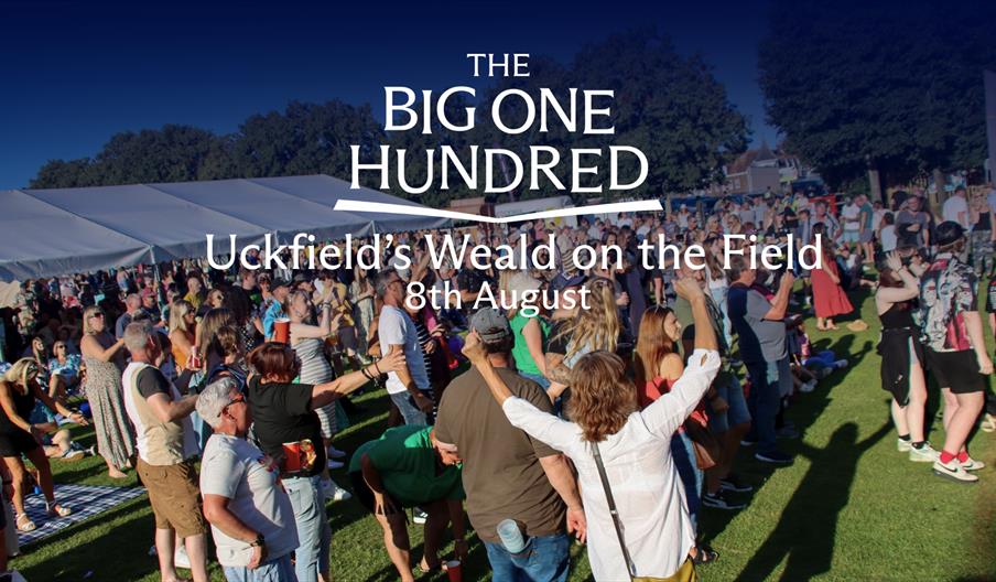 Crowd gathered at an outdoor event with tents and stalls, with “The Big One Hundred – Uckfield’s Weald on the Field 8th August” text overlaid.