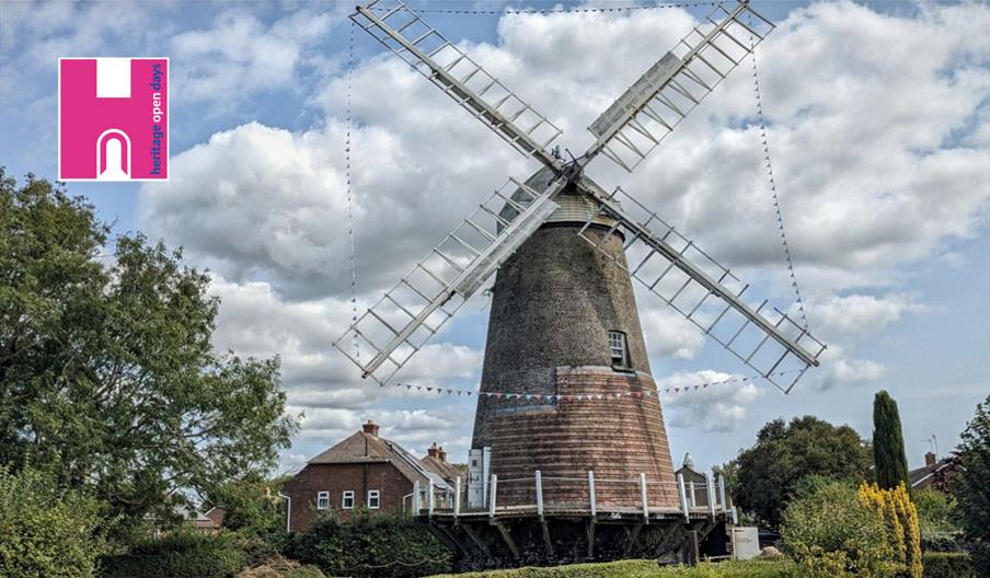 a post mill with a house on the side, and trees surrounding it