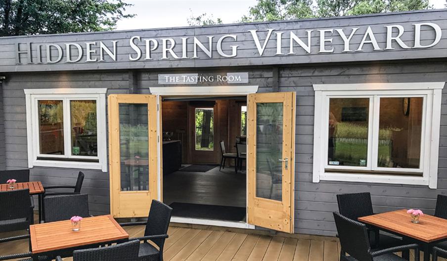 image of the vineyard tasting room - a wooden building with seating outside and inside