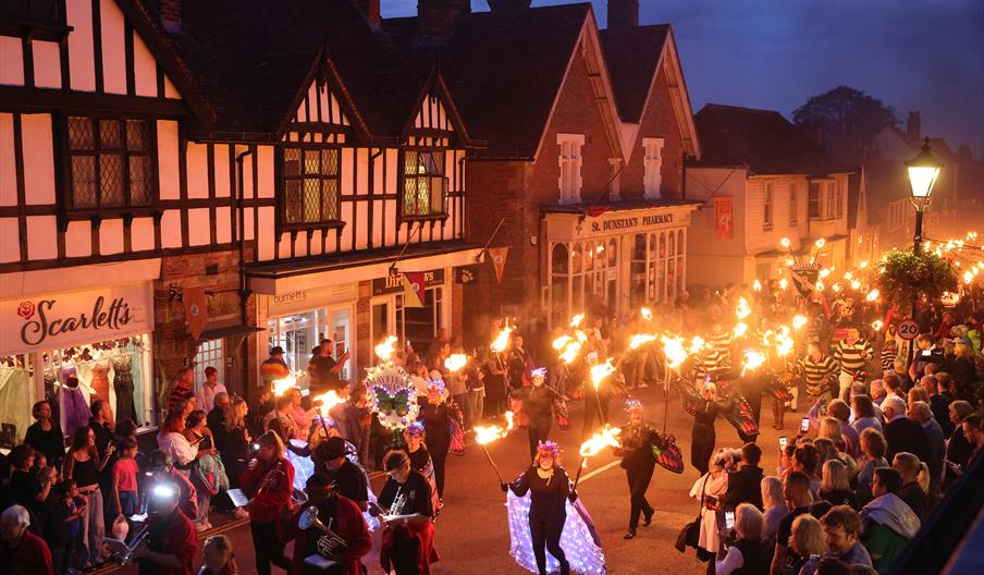 Torchlit procession through Mayfield High Street during the annual Mayfield Bonfire celebrations, with performers, illuminated costumes and crowds lin