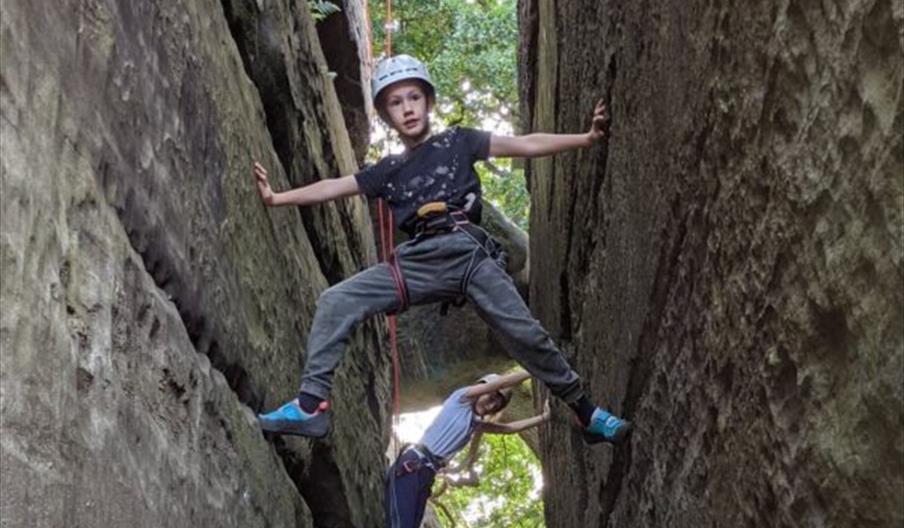 a kid rock climbing, in between two walls