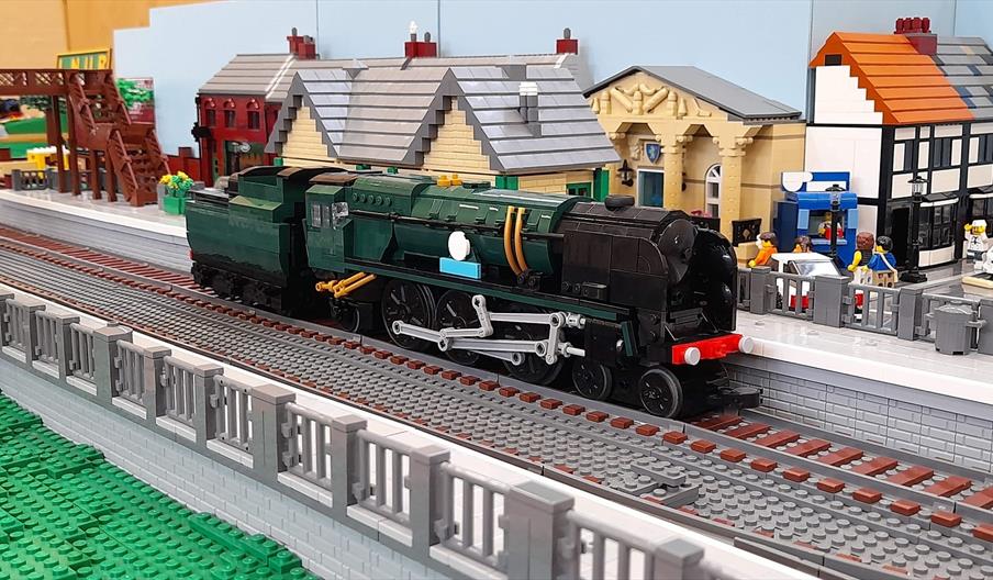 A lego train sitting on a train track at a lego station