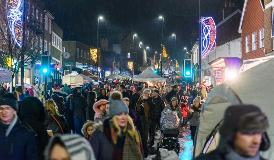 A high street at night filled with late night Christmas shoppers.