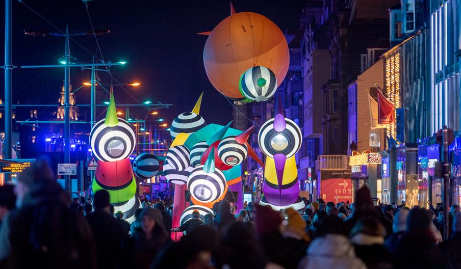A street parade of giant inflatable puppets in the dark