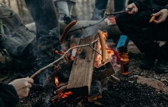 Group of people having a bbq around camp fire