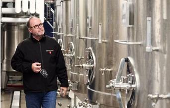 Image of a man walking through the tanks that make wine