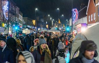 A high street at night filled with late night Christmas shoppers.
