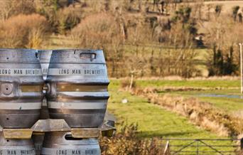 casks with long man brewery written on them with green fields in background