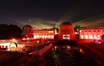 Picture of telescopes at observatory science centre in dark lit lighting with red mood lighting