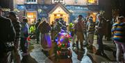 A group of people hanging outside a pub at night, ready for a bonfire procession