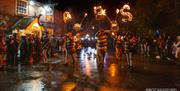 A group of people with torches, spelling out CPBS (Chiddingly Parish Bonfire Society), outside a pub