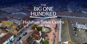 Aerial view of Hailsham Town Centre showing streets, shops and a central square, with “The Big One Hundred – Hailsham Town Centre 26th July” text over