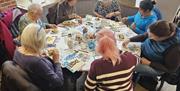 A group of adults sitting round a table making art