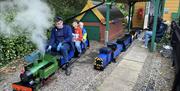 A miniature railway train, with a train driver and two children.