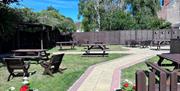 The garden at The Heron with a path in the middle and benches on the grass.