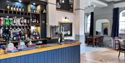 A photo of the bar in The Heron, with tables at the side.