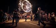 Participants carrying a large illuminated burning Poppy display through the streets during the East Hoathly Carnival and Bonfire celebrations, with sp