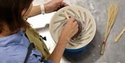 Image of a lady painting a plate with the Hakeme Brushwork