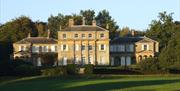 an impressive house with 3 buildings over 3 floors stood behind green gardens