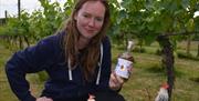 Gnina in the vineyard holding a in the loop drink sample