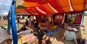Wellbeing and relaxation session taking place inside a colourful festival tent at One Love Festival, with participants gathered on mats beneath vibran