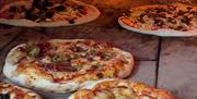 pizzas cooking in the wilderness wood-fired oven