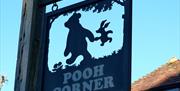 a black sign with the outline of winnie the pooh and piglet and the words pooh corner in gold