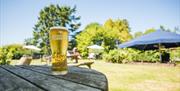 A pint on a wooden table outside of The Blue Anchor.