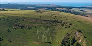 the outline of a white giant man carved in the side of the hill with two sticks surrounded by green countryside